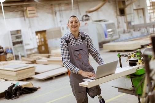 Behinderung am Arbeitsplatz Ein junger Mann mit einer Beinprothese an seinem Arbeitsplatz in einer Möbelfabrik.